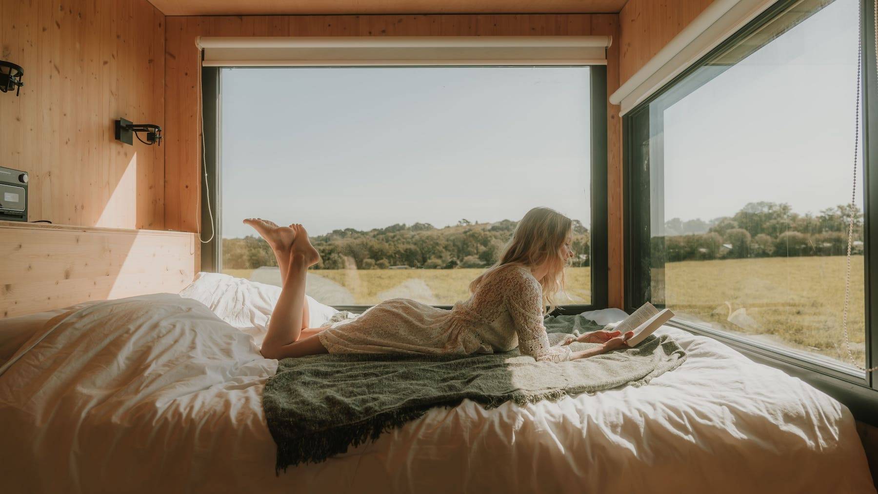 Femme qui lit un livre sur le lit de la Tiny House