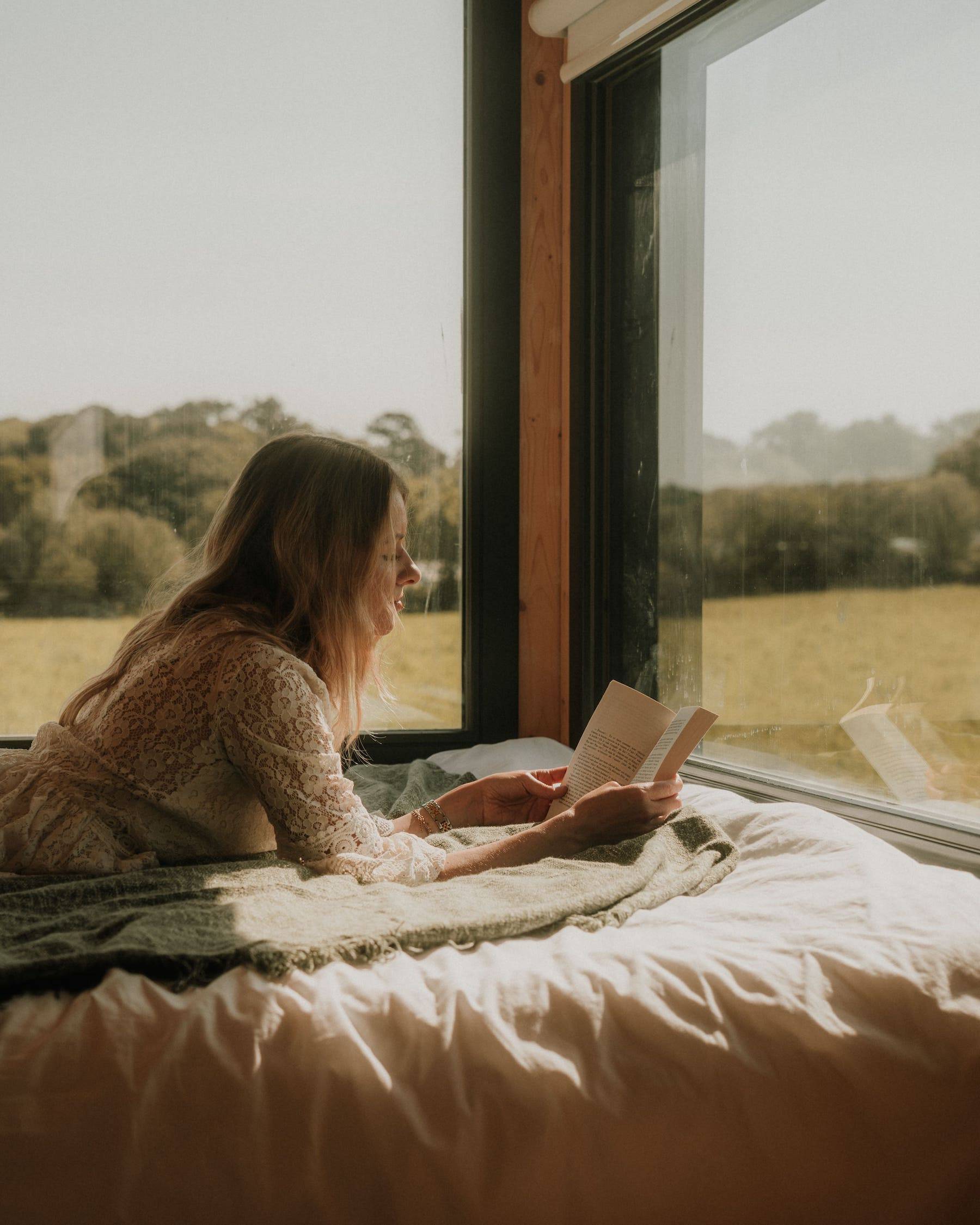 Femme qui lit un livre sur le lit de la Tiny House