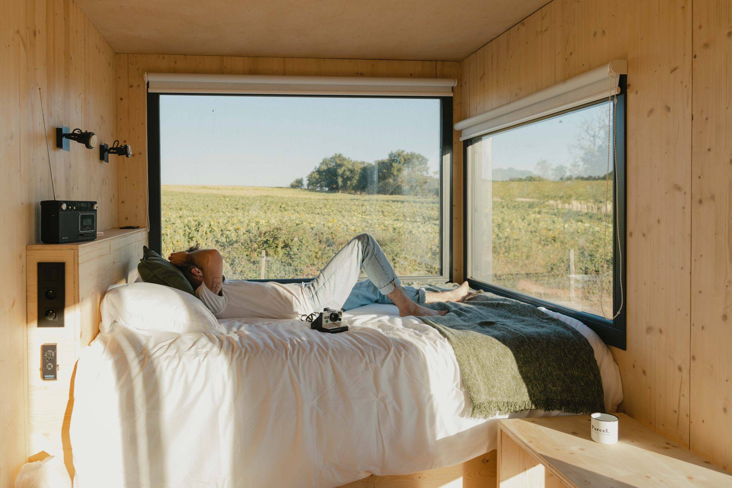 Man lying in Tiny House bed with camera