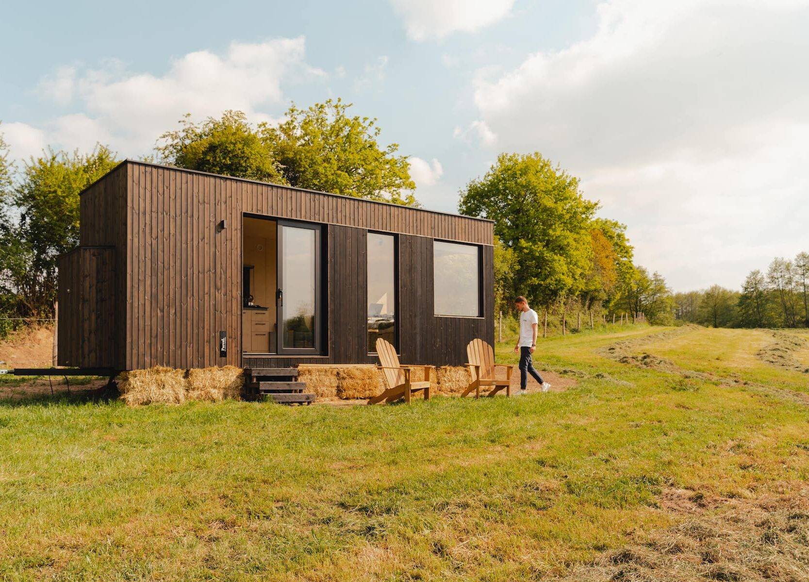 Man walking in front of the Tiny House in a field