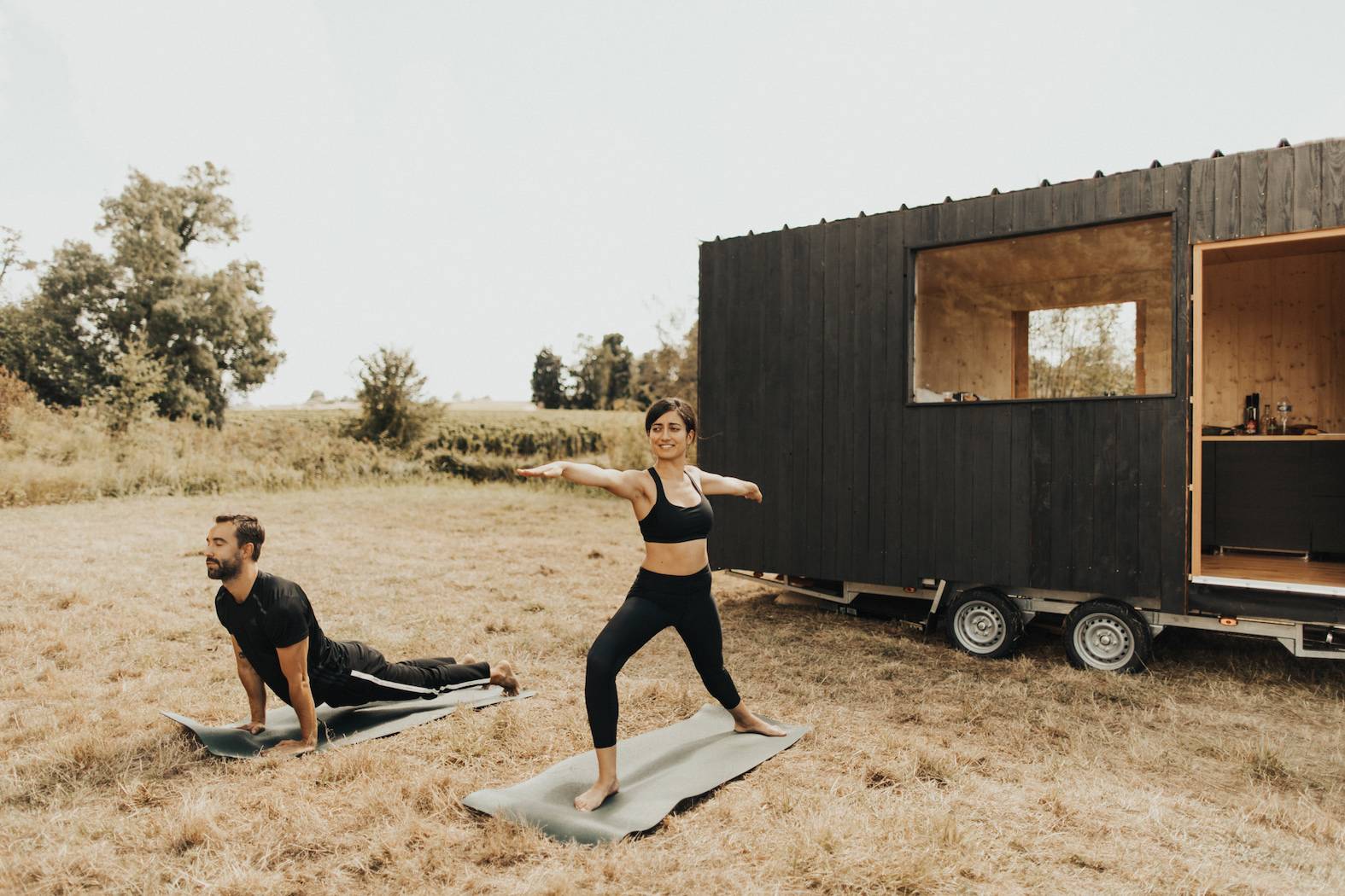 Yoga praktizierendes Paar vor dem Tiny House in Saint Emilion