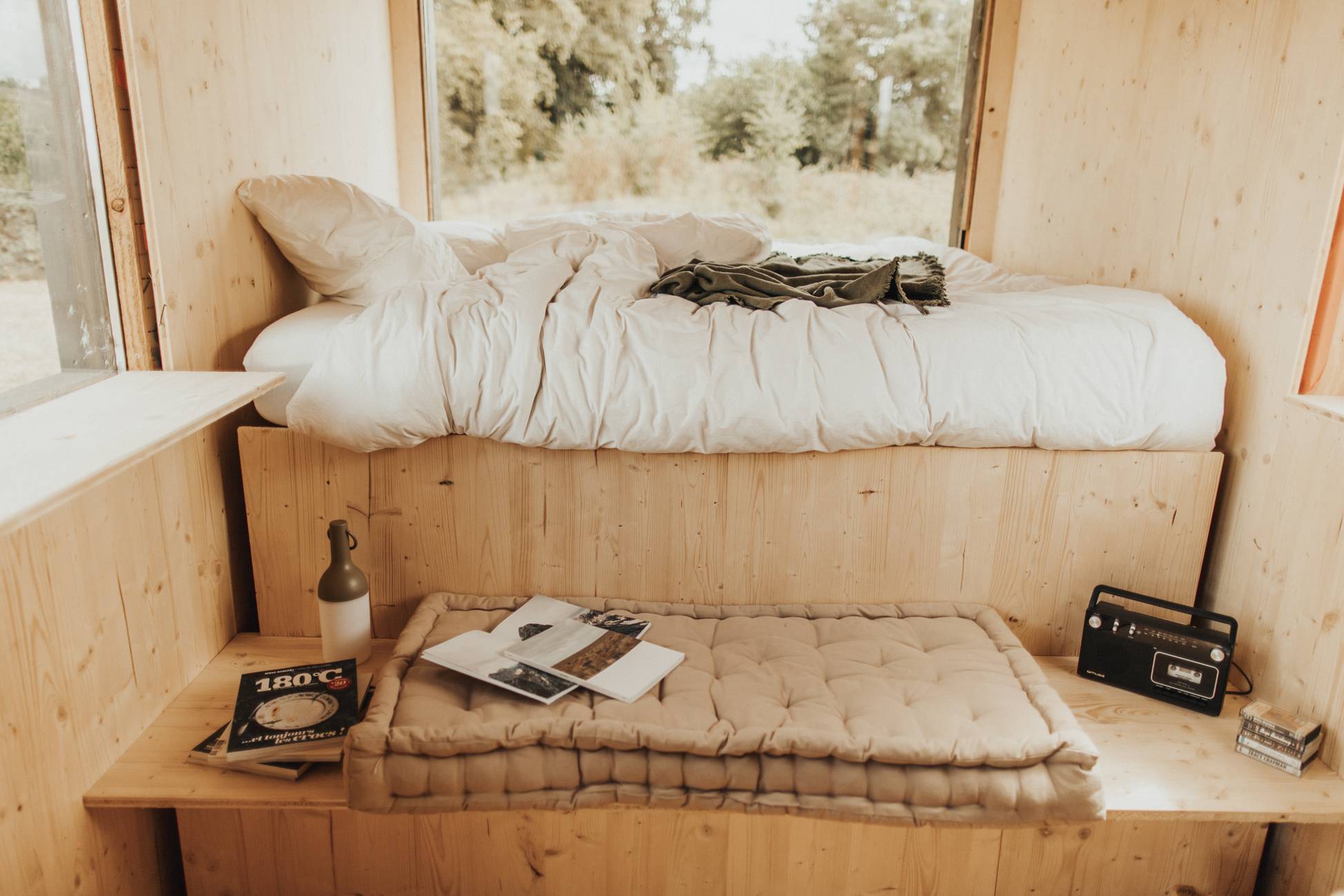 Letto nella Tiny House di St Emilion e panca con libri e radio a cassette