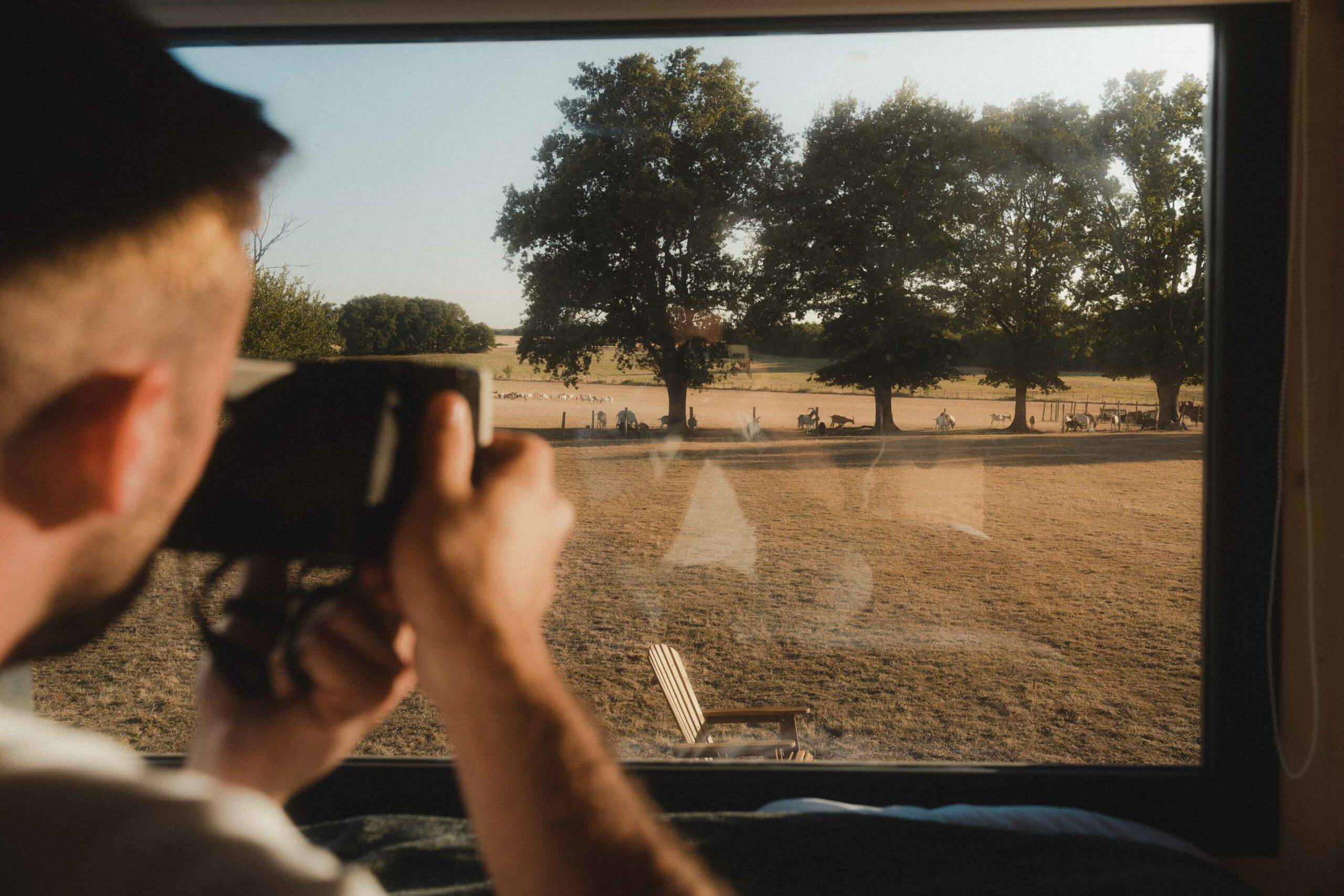Homme qui prend en photo les chèvres depuis le lit de la Tiny House