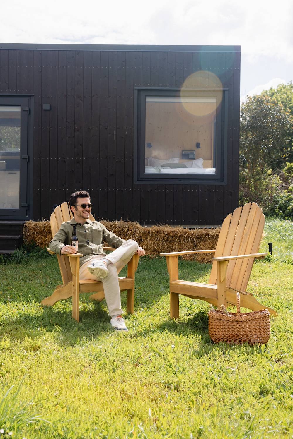 Un homme se repose dans un fauteuil devant la Tiny House au coeur des Yvelines