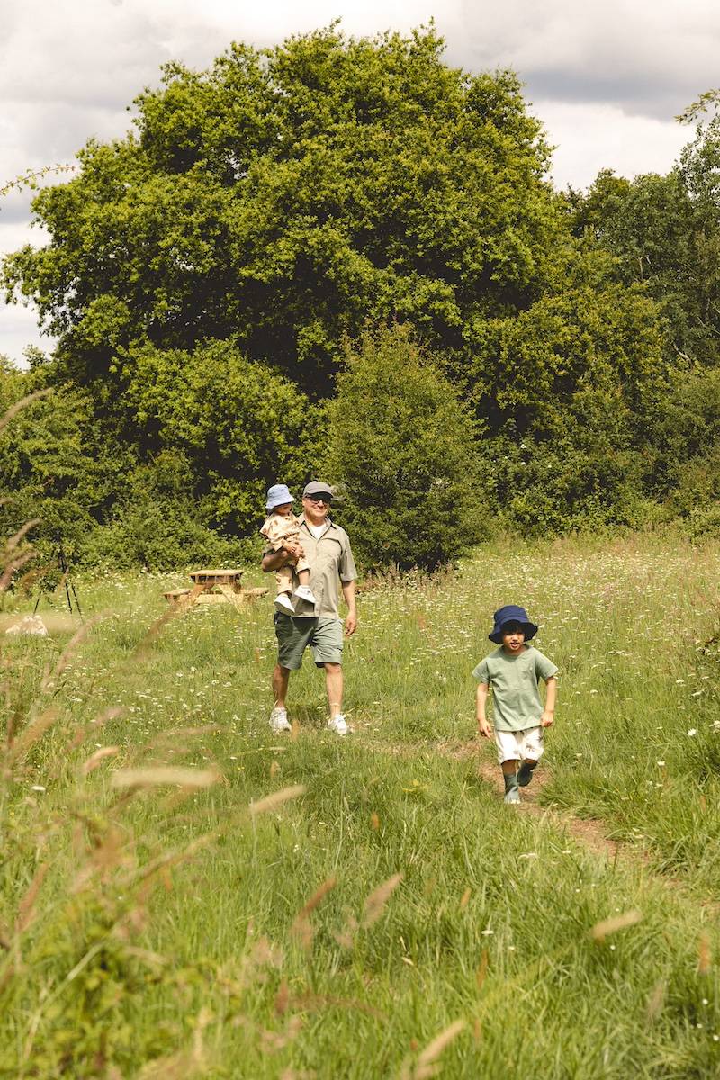Un papa et ses deux enfants marchent dans l'herbe