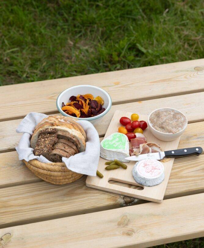 Un aperitivo con formaggio locale viene servito su un tavolo da picnic in legno.