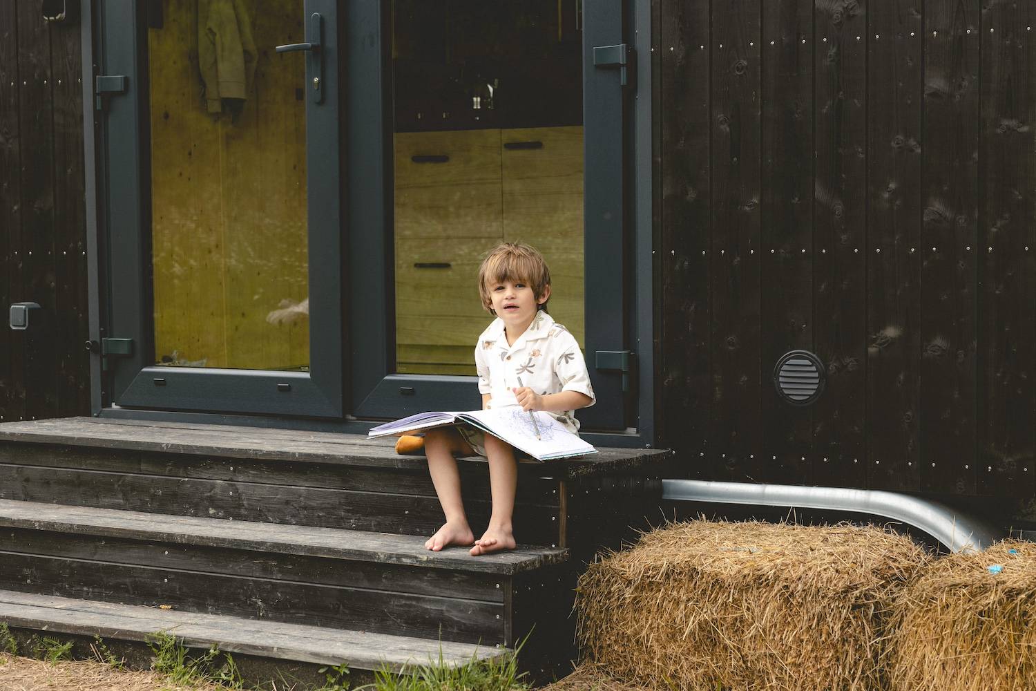 Un enfant colorie devant la Tiny House dans le Berry