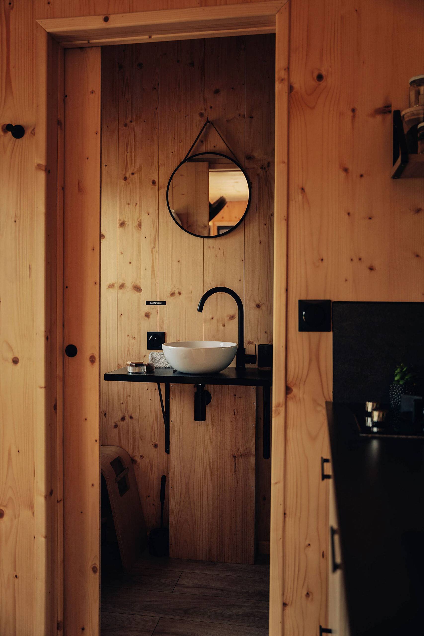 intérieur de la Tiny House, c'est la salle de bain en bois, il y a un lavabo et un miroir